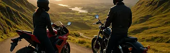 Zwei Motorradfahrer säumen das Bild, blicken auf den Sonnenuntergang über sanfte Hügel und ein Tal. Einer fährt ein rotes Sportmotorrad, der andere einen schwarzen Cruiser. Sie stehen auf einer Straße zwischen grasbewachsenen Hügeln und genießen die Aussi